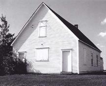 Photo de l'ancienne école de Gayton illustrant les deux portes d'entrée à la façade, ainsi que les fenêtres en partie barricadées. ; Village of Memramcook