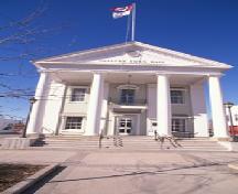 View of Napanee Town Hall, showing its two-storey, gable-roofed massing with a monumental pedimented portico with giant free-standing columns approached up broad steps, 1995.; Agence Parcs Canada / Parks Canada Agency, 1995.