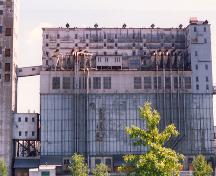 Vue de l'extérieur de l'élévateur 5 B, qui montre le fenêtrage de type industriel, concentré dans la partie supérieure et inférieure du bâtiment, 1995.; Parks Canada Agency / Agence Parcs Canada, J. Hallé, 1995.