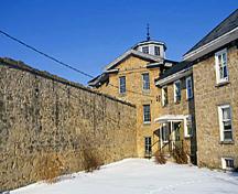 Vue de l'extérieur de la prison du comté de Huron, qui montre les murs hauts de deux étages, 1995.; Parks Canada Agency / Agence Parcs Canada, J. Butterill, 1995.