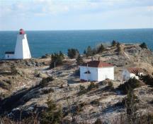 Image of the Swallowtail Light Keeper's House in winter, 2010, showing the windows boarded up.  Swallowtail Lighthouse is on the left.; Grand Manan Historical Society