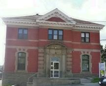 Cette image montre la façade avant bien entretenue constituée de briques rouges et de détails en grès; Village of Hillsborough