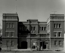 Vue arrière du manège militaire de la rue McGregor, où l'on peut apercevoir le rapport symétrique des fenêtres à guillotine à plusieurs carreaux et des portes surmontées d’impostes, 1994.; Department of National Defence / Ministère de la Défense nationale, 1994.