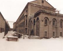 Vue de l'atelier est, qui montre le volume sur trois étages avec un toit à deux versants en pente moyenne, 1989.; Travaux publics Canada / Public Works Canada, 1989.