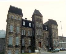 Vue de la façade du Bureau de l’administration, qui montre la maçonnerie, composée de murs de parement en pierre de grès et de pierres d’angle taillées et de couleur contrastante, 1990.; Correctional Service of Canada / Service correctionnel du Canada, 1990.