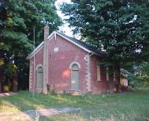 Vue de l'extérieur de l'ancienne école de rang d'Atha, qui montre la configuration des ouvertures avec deux portes sur la façade avant (une pour chaque sexe), 2005.; Department of Public Works and Government Services / Ministère des Travaux publics et services gouvernementaux, Don Macdonald, 2005.