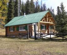 Vue générale du chalet des gardes du parc de Brazeau, qui montre son esthétique rustique, qu’exprime l’utilisation de matériaux disponibles localement comme le bois, 2005.; Parks Canada Agency / Agence Parcs Canada, 2005.