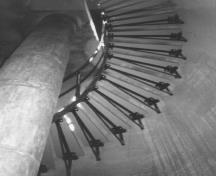 Vue de l'intérieur du phare, qui montre l’escalier en colimaçon, qui mène à chaque niveau et au fanal, 1990.; Parks Canada Agency / Agence Parcs Canada, 1990.
