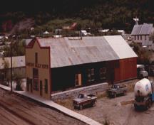 General view of the Dawson Daily News, showing the asymmetrical, boomtown-fronted street elevation with ‘Dawson Daily News’ painted across it in large letters, 1988.; Parks Canada Agency / Agence Parcs Canada, J. Mattie, 1988.
