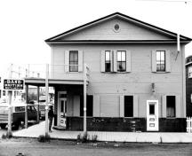 Façade of the Bank of British North America, showing the pedimented gable roof, the circular ventilator piercing the pediment, and the overhanging eaves, 1988.; Parks Canada Agency / Agence Parcs Canada, J. Mattie, 1988.