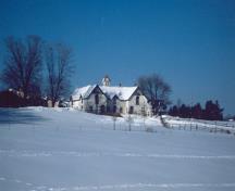 Vue de la façade principale de l'écurie, qui montre l’emplacement des portes et des grandes fenêtres à arc en plein-cintre, 1991.; Parks Canada Agency / Agence Parcs Canada, E. Tumark, 1991.