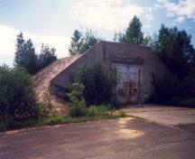 Vue de la façade générale du bâtiment 1082, qui montre l’utilisation de béton coulé pour la construction, 1989.; Parks Canada Agency / Agence Parcs Canada, 1989.