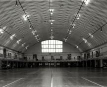 Interior view of the Fort York Armoury, showing the spartan interior finishes and the balcony design found in the drill hall, 1985.; Ministère de la Défense nationale / Department of National Defence, 1985.