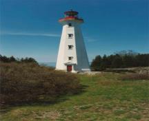 General view of the Light station Tower, showing its simple massing, consisting of a slim octagonal structure with prominent lantern, and the four levels of six-paned windows, 1990.; Department of Transport / Ministère des Transports, 1990.