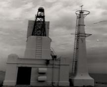 General view of the Former Foghorn Building, showing the small, square massing with flat-roof supporting a concrete tower supporting the pierhead light and foghorn, 1988.; Parks Canada Agency / Agence Parks Canada, 1988.