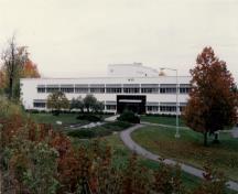 General view of Building M-20, showing the low massing of the main two-storey block with three, three-storey wings and flat roof, 1990.; National Research Council of Canada / Conseil national de recherches du Canada, 1990.
