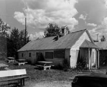 Corner view of the Engineering Office (Building 19), showing its horizontal wood siding and its rooftop ventilator, 1988.; Parks Canada Agency / Agence Parcs Canada, 1988.