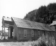 General view of the Machine Shop, showing its simple rectangular shape, its gable roof and its corrugated metal siding and roof covering, 1988.; Parks Canada Agency / Agence Parcs Canada, 1988.