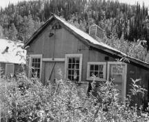 View of the main entrance to the Tin Shop, showing the arrangement and detailing of the double doors and the windows of the front gable, 1988.; Agence Parcs Canada / Parks Canada Agency, 1988.