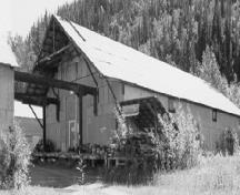 Corner view of Warehouse 2, showing the building’s simple, warehouse form and massing including the gable roof, 1988.; Agence Parcs Canada / Parks Canada Agency, 1988.