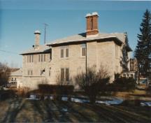 Vue de la façade latérale du centre correctionnel communautaire Portsmouth, qui montre un toit en croupe bas complété d’un large avant-toit et percé de grandes cheminées latérales en brique, 1991.; Correctional Service of Canada / Service correctionnel du Canada, 1991.