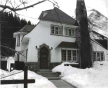 Façade avant de la résidence du directeur, qui montre le mariage du stuc à fini grossier avec les boiseries et la pierre, vers 1991.; Agence Parcs Canada / Parks Canada Agency, ca./vers 1991.