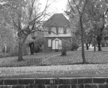 View of the front of the Defensible Lockmaster's House, showing the placement of the windows and doors and the loopholes on either side of the main entrance, 1990.; Parks Canada Agency / Agence Parcs Canada, James De Jonge, 1990.
