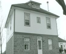 View of the front of the Defensible Lockmaster's House, showing the placement of the windows and doors on both floors, 1990.; Parks Canada Agency / Agence Parcs Canada, James De Jonge, 1990.