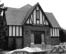 Façade du Pavillon d'information, qui montre les éléments inspirés du style néo-Tudor, notamment l’emploi répandu de moellons bruts et de pans de bois complétés par un crépi peint et d’éminents pignons, 1991.; Parks Canada Agency / Agence Parcs Canada, C. Wittig, 1991.