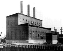 Vue générale de la centrale à vapeur de l’Ottawa Electric Railway Company, montrant la volumétrie en gradins, formée d’un bloc d’un étage et d’un autre de deux étages, avec une petite annexe du côté ouest, 1958; COA, OER Collection, CA-15021, 1958.