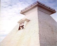 Vue des détails du phare Mabou démontrant ses proportions et ses détails classiques y compris les ouvertures coiffées d’un fronton, les fenêtres à guillotine de six carreaux sur six et la corniche, 2002.; Public Works Canada / Ministère des Travaux publics, 2002.