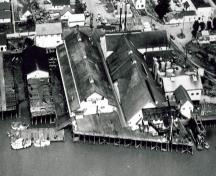 Aerial view of its siting, built on wharf structures out over the river.; Parks Canada Agency / Agence Parcs Canada