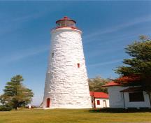 General view showing the sparse detailing, including plain stone sills of the small staggered windows and the smooth surrounds of the round-headed doorway.; Parks Canada Agency / Agence Parcs Canada