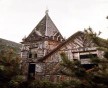 Exterior view of St. Andrew's Presbyterian Church, showing its varied texture and colour created by the use of short lengths of split slabs (bark retained) set in several courses and placed in varying patterns, 1971.; Parks Canada Agency/Agence Parcs Canada, 1971.