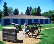 Vue générale des casernes de Butler montrant la remise de canons avec son corps de bâtiment rectangulaire de plain-pied et son toit en croupe bas, avec sa façade principale à sept baies de portes doubles de hangar, 1993.; Parks Canada Agency / Agence Parcs Canada, B. Morin, 1993.