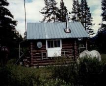 Vue de la façade laterale du chalet de patrouille des gardes du parc de Topaz, où l'on peut apercevoir les murs faits de rondins écorcés de 8 à 10 pouces, posés à l’horizontale et assemblés en sabot, 1997.; Parks Canada Agency / Agence Parcs Canada, 1997.