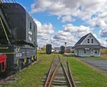 Vue vers l'est de la rue Main. Du matériel ferroviaire lourd en avant-plan et la gare reconstruite en arrière-plan. ; Village of Hillsborough
