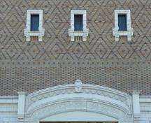 Vue détaillée du Théâtre Royal, qui montre le parement de terra-cotta du rez-de-chaussée imitant la pierre, la bande de briquetage polychrome à motifs en losange, 2011.; Parks Canada Agency / Agence Parcs Canada, Andrew Waldron, 2011.