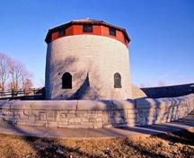 General view of Murney Tower showing the squat round massing of the tower with hive-like caponiers at the base and a conical roof as well as its symmetry, with the circumference and height of the tower in equal proportion.; Parks Canada Agency/ Agence Parcs Canada, J. Butterill, 1994.