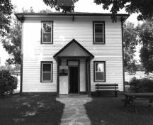 Façade of the Defensible Lockmaster's House, showing its clapboard-clad, hipped-roofed domestic exterior form, 1989.; Parks Canada Agency / Agence Parcs Canada, Couture, 1989.