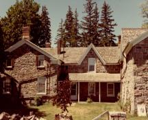 Vue de l'entrée principale de la ferme Thistle Ha’, qui montre la maison avec la porte d’entrée centrale, les ouvertures latérales et l'imposte, 1991.; Parcs Canada | Parks Canada