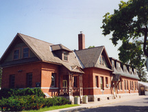Vue de l'extérieur du bâtiment des récoltes céréalières, qui montre la composition et les détails du porche avant, en particulier les colonnes tournées, 1995.; Parks Canada Agency / Agence Parcs Canada, 1995.