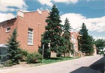 View of the main façade of the RCMP Gymnasium and Pool Building, showing the raised and stepped end gables capped by decorative white stonework, 1986.; Royal Canadian Mounted Police / Gendarmerie royale du Canada, 1986.